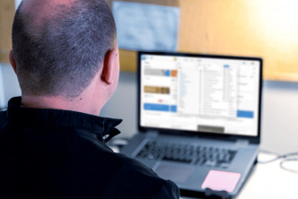 man at desk uses Logos on laptop