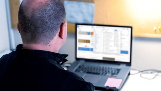 man at desk uses Logos on laptop