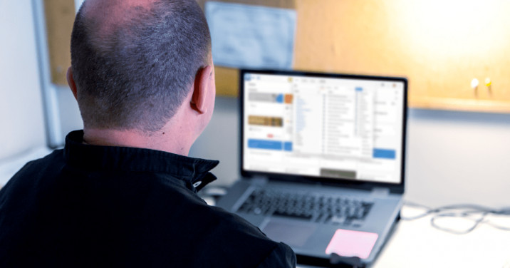 man at desk uses Logos on laptop