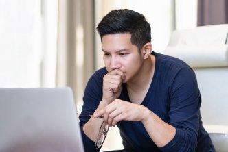 Man reading on a computer for a post about theological journals