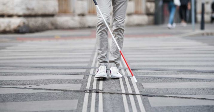 blind person walking across the street