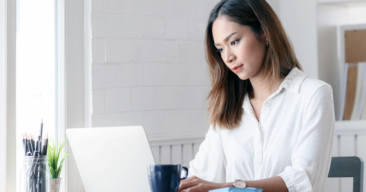 woman at desk uses Logos Bible Software on laptop