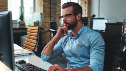 man at desk looks at benefits of Logos upgrade on his desktop computer