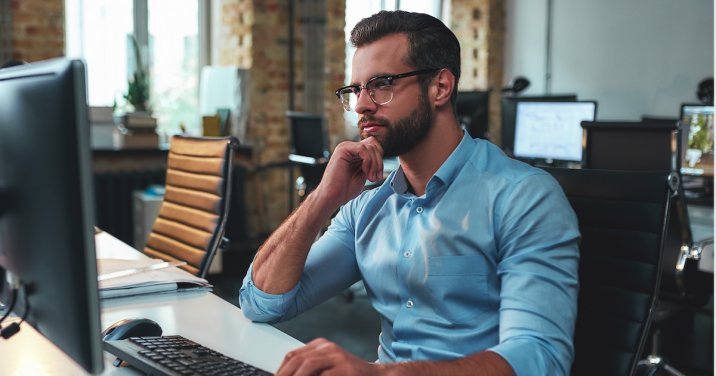 man at desk looks at benefits of Logos upgrade on his desktop computer