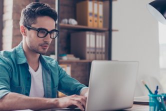 man at desk looks at Logos Bible Software on laptop