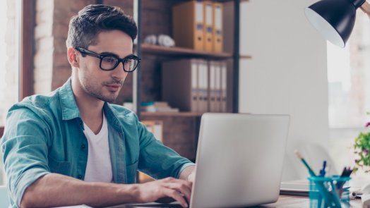 man at desk looks at Logos Bible Software on laptop