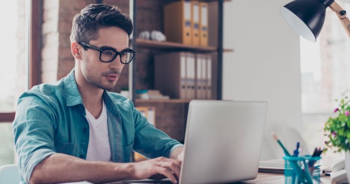 man at desk looks at Logos Bible Software on laptop