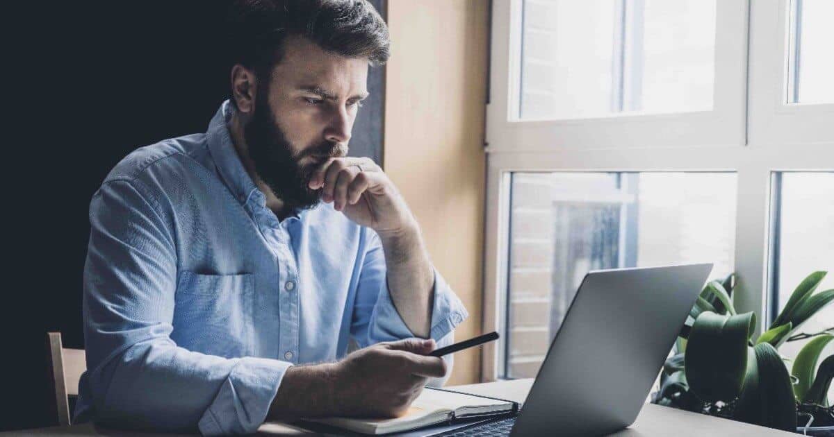 Man at desk studying the Bible on a laptop