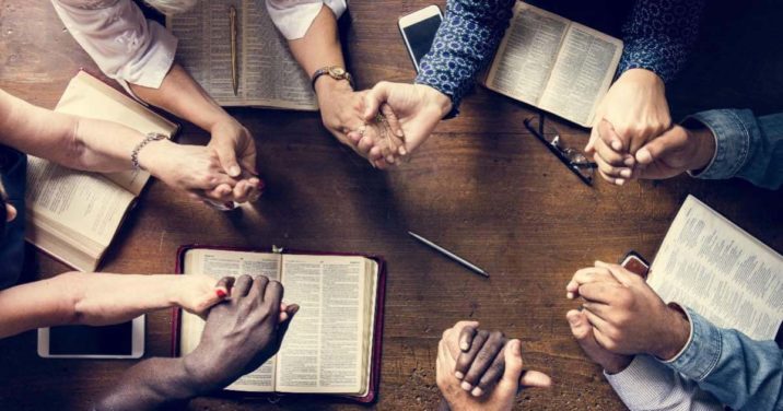 people who know the importance of prayer praying around a table, hands joined