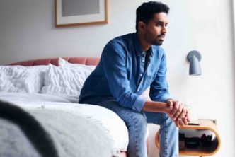 pastor sitting on the edge of his bed thinking about his mental health