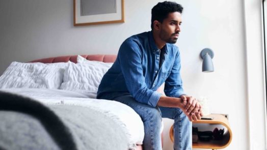 pastor sitting on the edge of his bed thinking about his mental health