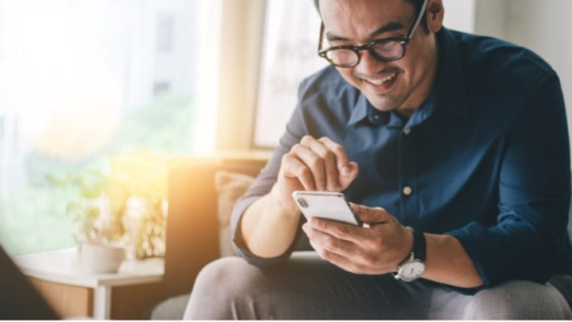 man on couch studies the Bible on his phone with a free Bible app