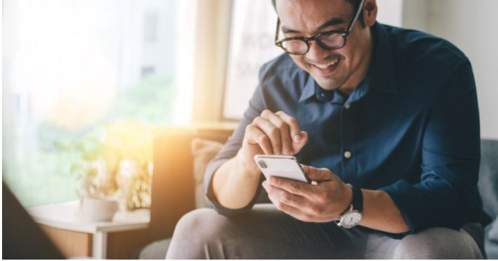 man on couch studies the Bible on his phone with a free Bible app