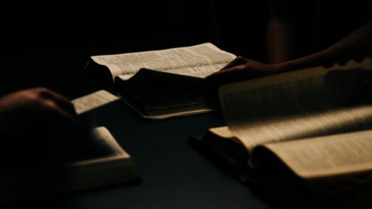 three open Bibles on a table being used by a small group studying how to guard against heresy