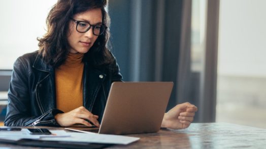 woman at desk studies the Bible with Logos Bible Software on laptop