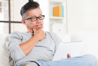 man sitting on couch reading devotional on tablet