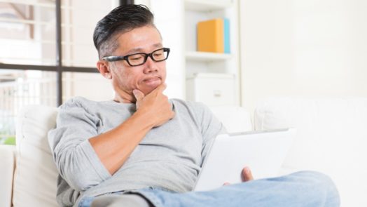 man sitting on couch reading devotional on tablet