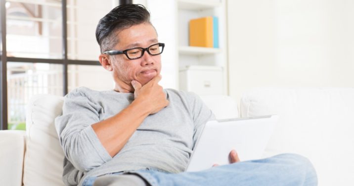 man sitting on couch reading devotional on tablet