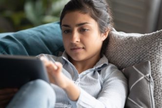 woman on couch reading devotional Bible commentary on tablet