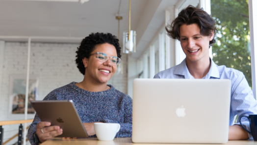 man and woman at desk look at Logos 10 on an iPad and laptop