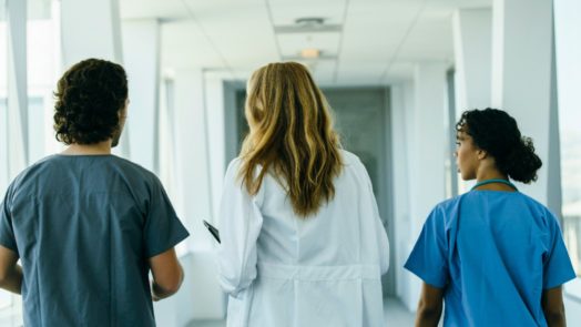 a doctor and two nurses walk down a hospital hall discussing monkeypox