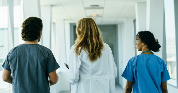 a doctor and two nurses walk down a hospital hall discussing monkeypox