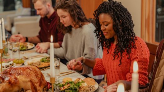 friends at table hold hands to pray for their meal after reading Thanksgiving Bible verses
