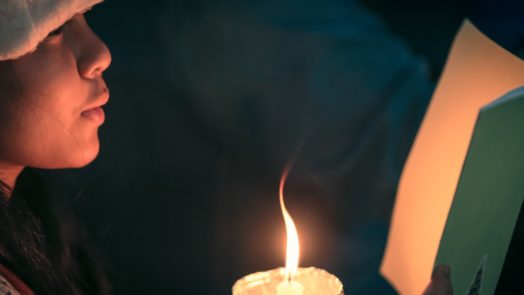 girl at candlelight service sings Christian Christmas songs