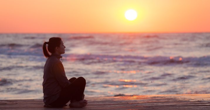 woman on beach at sunset contemplates grace